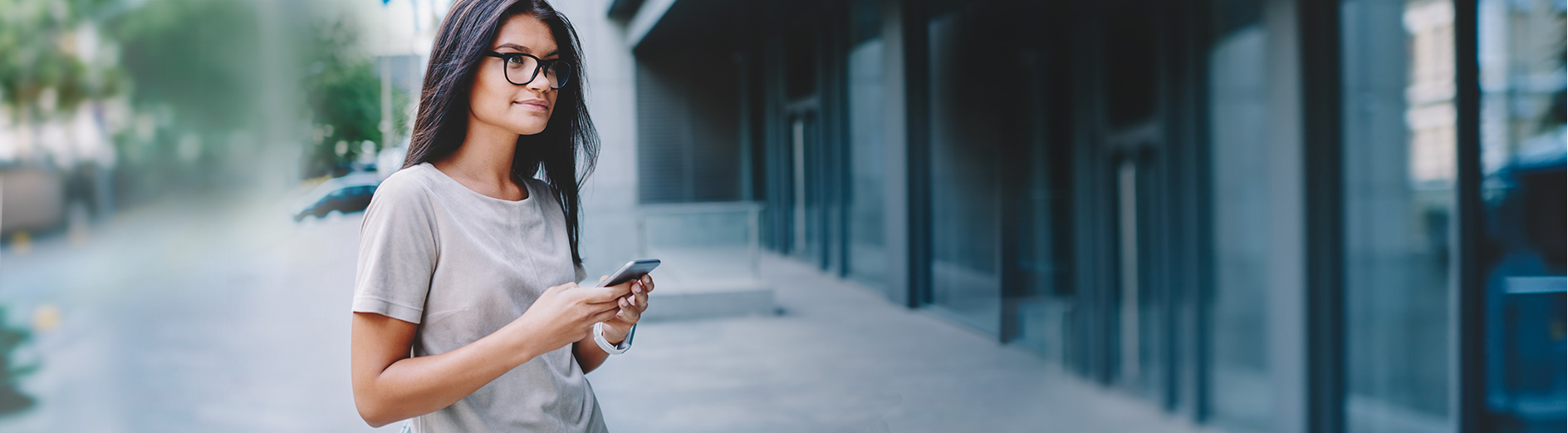 Young woman waiting outside building with her mobile ticket